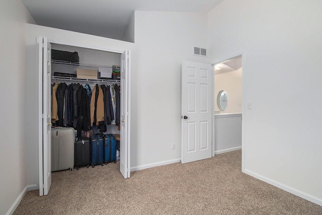 unfurnished bedroom featuring lofted ceiling, light carpet, visible vents, baseboards, and a closet