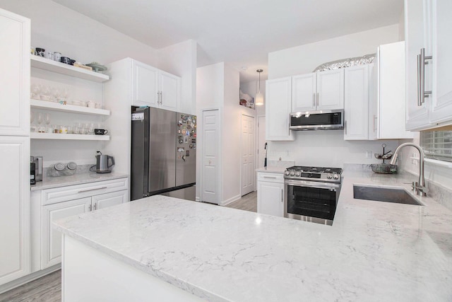 kitchen with stainless steel appliances, a sink, white cabinets, light stone countertops, and open shelves