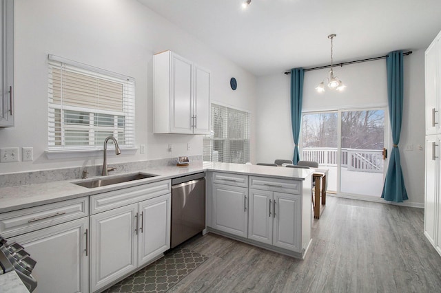 kitchen featuring a peninsula, stainless steel dishwasher, white cabinetry, pendant lighting, and a sink