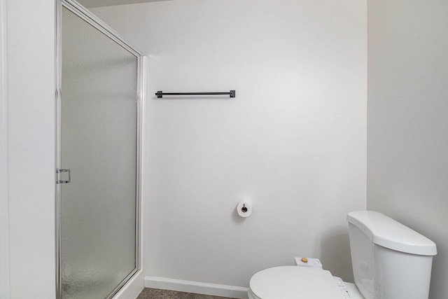 bathroom featuring baseboards, a shower stall, and toilet