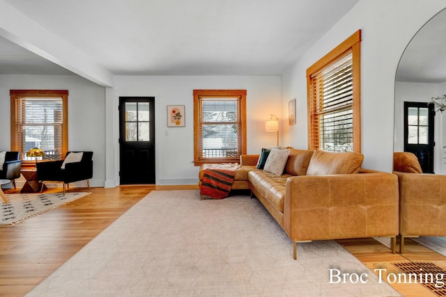 living area featuring light wood-style flooring and arched walkways