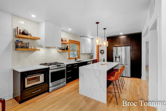 kitchen featuring stainless steel appliances, a kitchen breakfast bar, a center island, open shelves, and decorative light fixtures