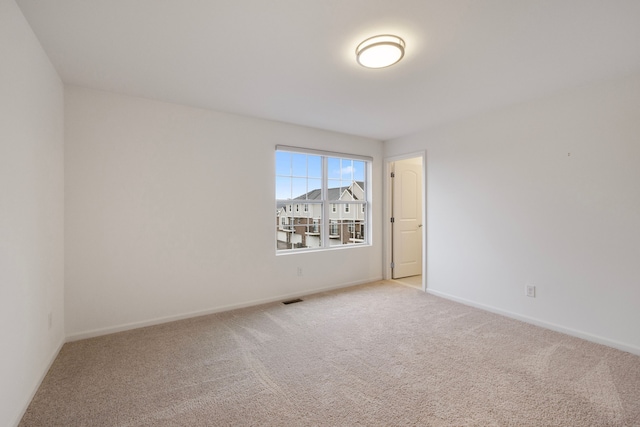 empty room with light carpet, visible vents, and baseboards