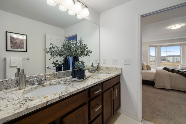 ensuite bathroom with double vanity, connected bathroom, baseboards, and a sink