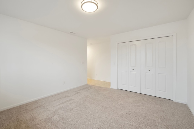 unfurnished bedroom featuring a closet, baseboards, and carpet flooring