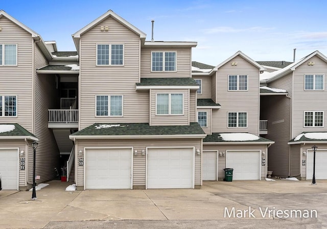 view of property featuring roof with shingles, driveway, and an attached garage