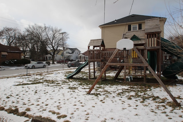 snow covered playground with a residential view and a playground