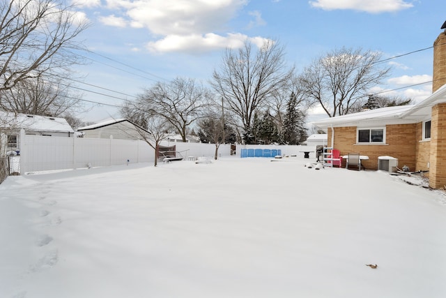 yard covered in snow featuring fence and central AC unit