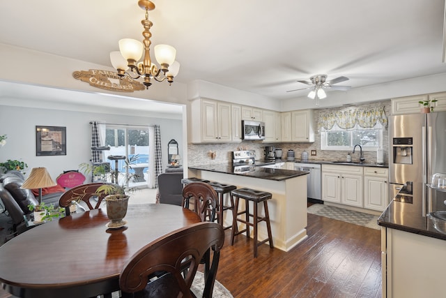 dining room featuring dark wood-type flooring, a wealth of natural light, and ceiling fan with notable chandelier