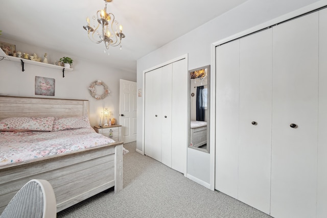 bedroom featuring light carpet, a notable chandelier, and multiple closets