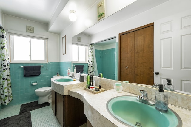 bathroom featuring a sink, tile walls, toilet, and double vanity