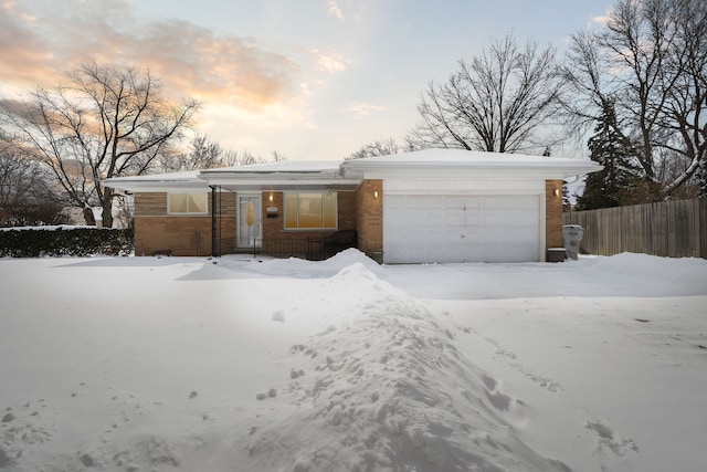 ranch-style home featuring brick siding, an attached garage, and fence