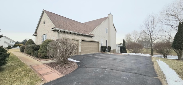 view of side of home featuring driveway, a shingled roof, and a chimney