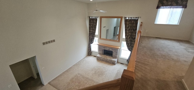 living room featuring ceiling fan, light colored carpet, visible vents, baseboards, and a brick fireplace