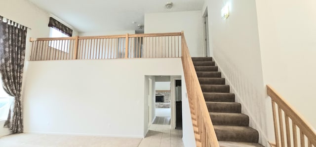 stairs with tile patterned flooring, a towering ceiling, and baseboards