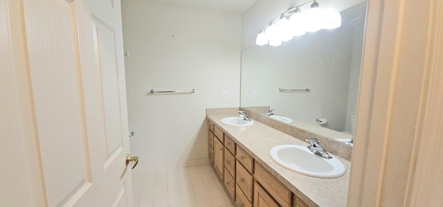 full bathroom with double vanity, a sink, toilet, and baseboards