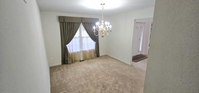 empty room with a chandelier, carpet floors, and baseboards