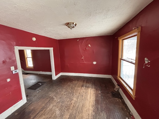 unfurnished room featuring a healthy amount of sunlight, baseboards, and wood finished floors