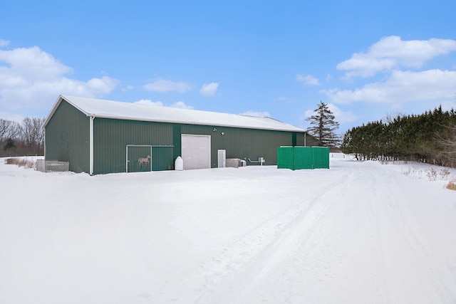 snow covered structure with an outbuilding and a pole building