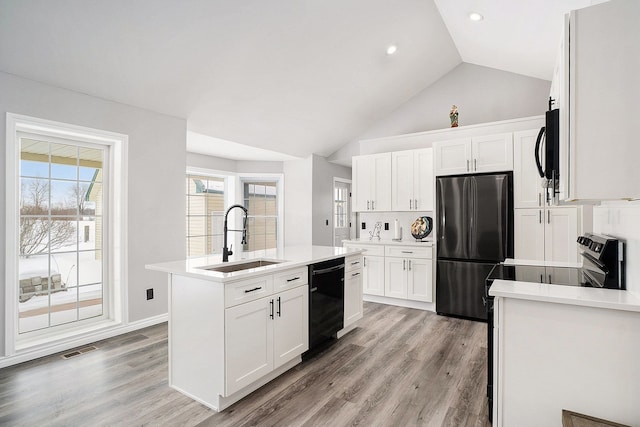 kitchen with black appliances, white cabinetry, light countertops, and a sink