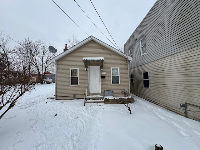 snow covered rear of property featuring a chimney