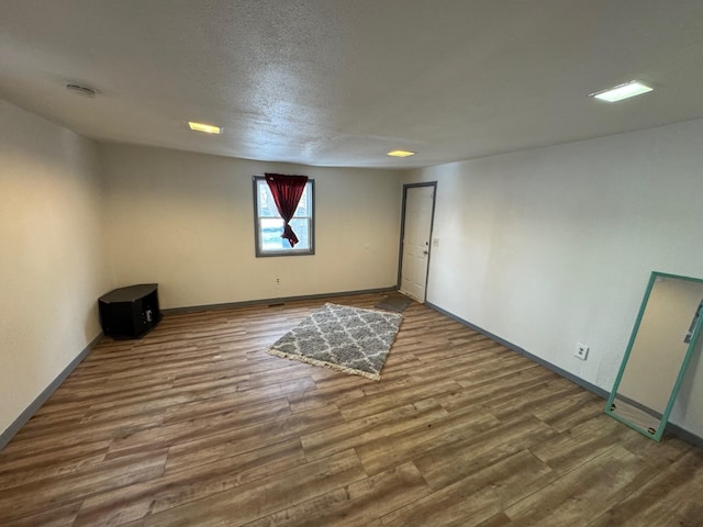 basement with a textured ceiling, baseboards, and wood finished floors