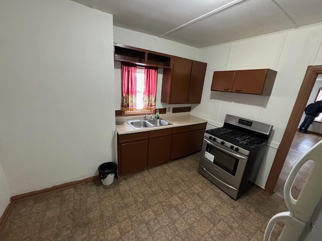 kitchen featuring dark brown cabinetry, tile patterned floors, light countertops, a sink, and gas stove