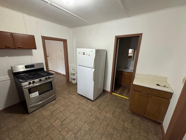 kitchen featuring light countertops, freestanding refrigerator, stainless steel gas range, baseboards, and tile patterned floors