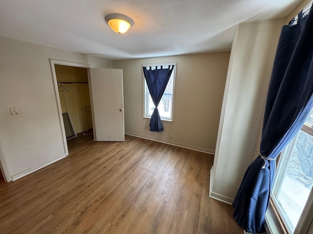 unfurnished bedroom featuring a closet, baseboards, and wood finished floors