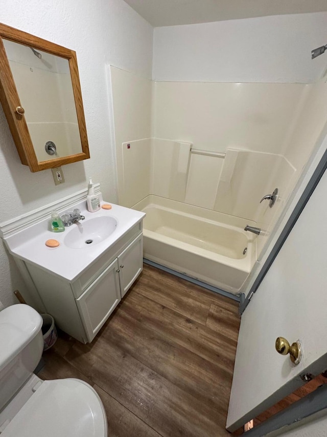 bathroom featuring  shower combination, vanity, toilet, and wood finished floors