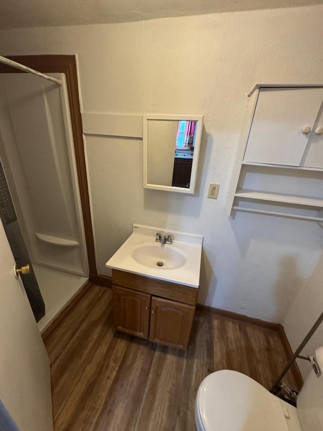 full bath with toilet, a shower stall, vanity, and wood finished floors