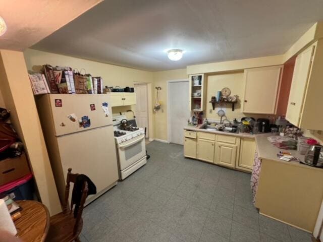 kitchen featuring cream cabinets, white appliances, a sink, light countertops, and tile patterned floors