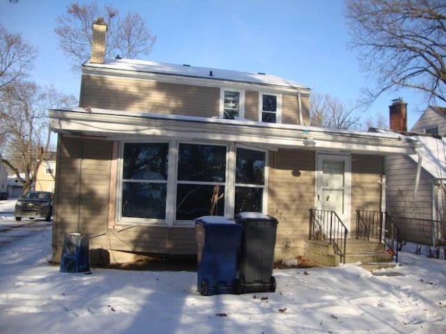 snow covered back of property with a chimney