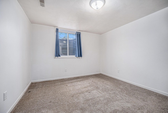 empty room with baseboards, visible vents, a textured ceiling, and carpet flooring