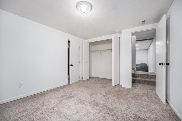 unfurnished bedroom featuring light carpet, visible vents, baseboards, and a closet