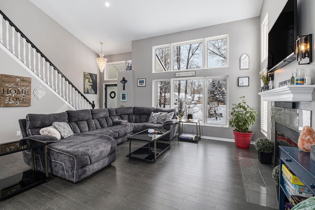 2839 Davista Dr, Highland, MI 48356 - living area with a towering ceiling, dark wood finished floors, a tile fireplace, stairs, and baseboards
