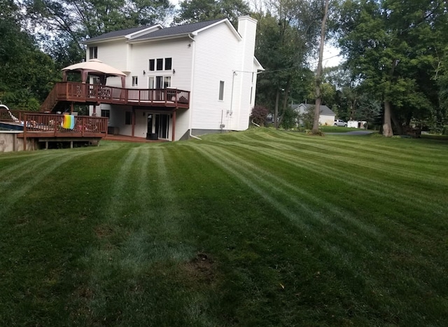 2839 Davista Dr, Highland, MI 48356 - back of house with a gazebo, a wooden deck, a lawn, and a chimney
