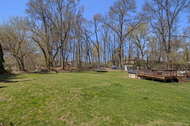2839 Davista Dr, Highland, MI 48356 - view of grassy yard featuring a trampoline, a wooden deck, and a fire pit