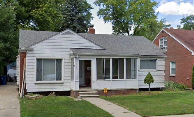 bungalow-style house featuring a shingled roof, a front yard, and a chimney