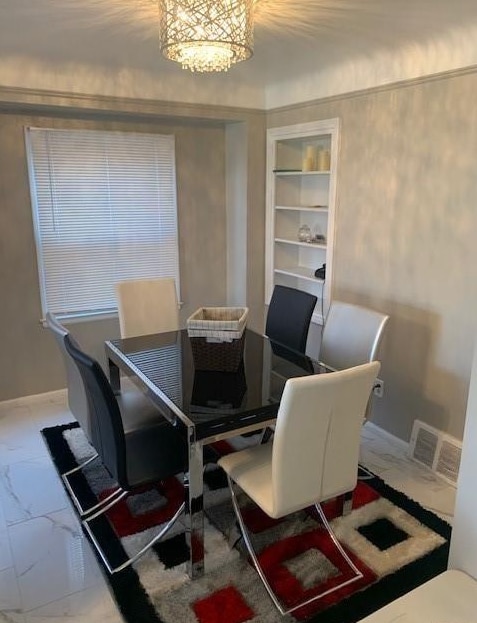 dining room featuring built in shelves, marble finish floor, visible vents, and baseboards