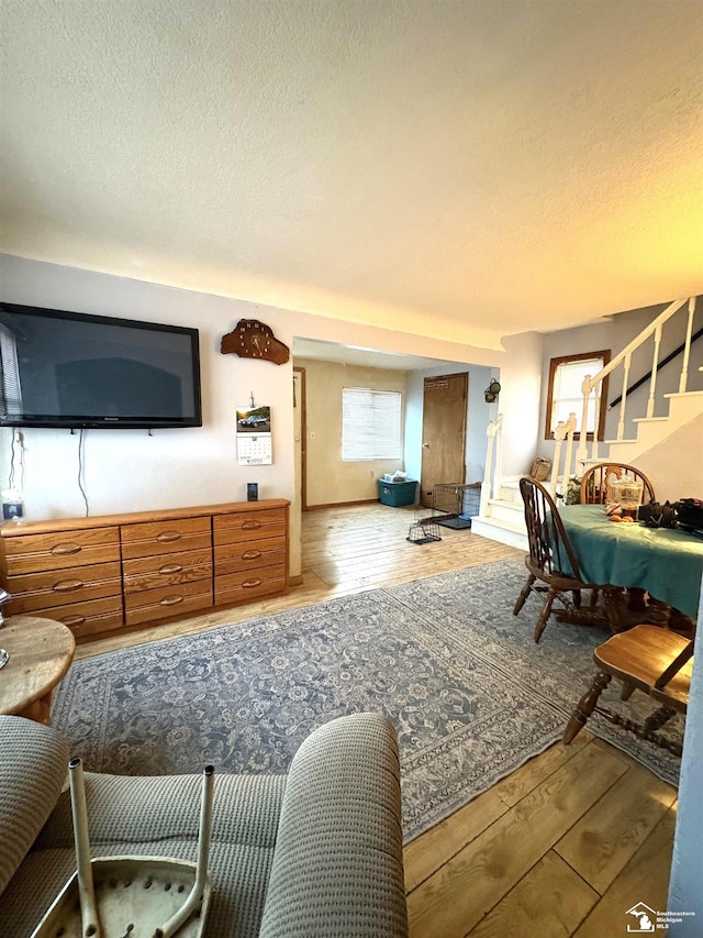 living room featuring a textured ceiling, stairway, and light wood-type flooring