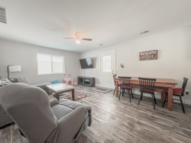 living area with visible vents, ceiling fan, baseboards, and wood finished floors