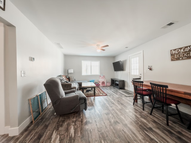 living area with a ceiling fan, visible vents, baseboards, and wood finished floors