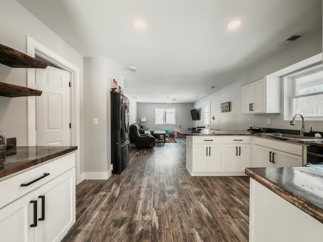 kitchen with dark countertops, freestanding refrigerator, and white cabinets