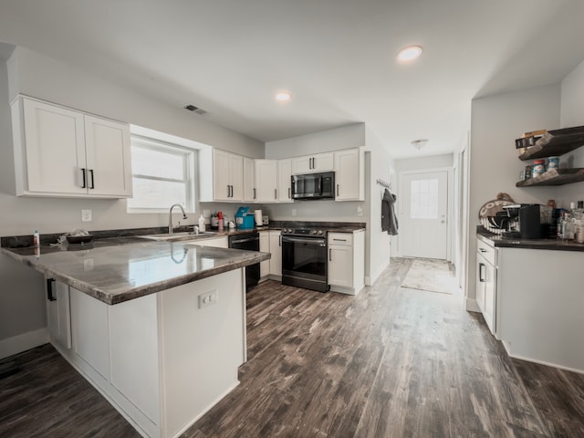 kitchen with visible vents, white cabinets, a sink, a peninsula, and black appliances