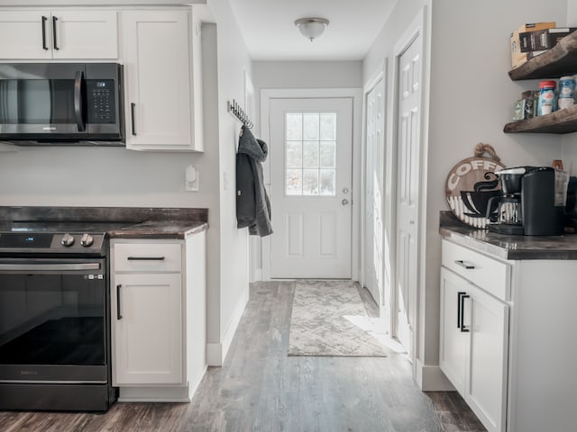 kitchen featuring dark countertops, stainless steel electric range oven, and white cabinets