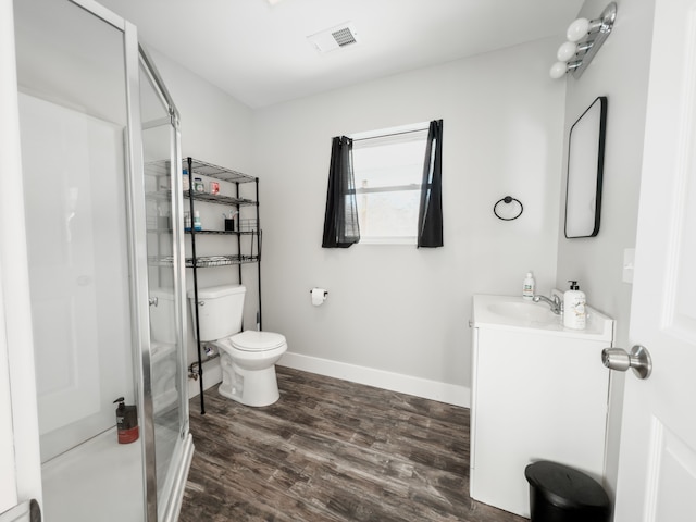 bathroom with toilet, wood finished floors, visible vents, vanity, and a stall shower