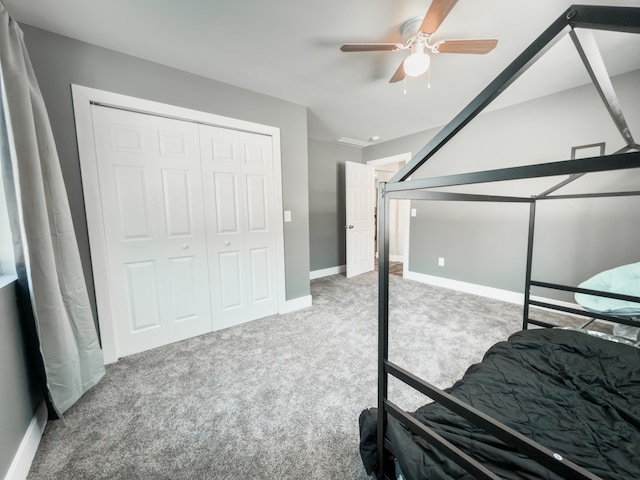 carpeted bedroom with ceiling fan, a closet, and baseboards