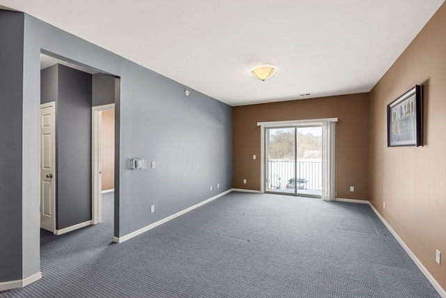 empty room featuring dark colored carpet and baseboards