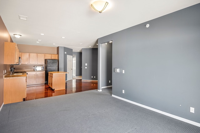 kitchen featuring light brown cabinets, carpet floors, open floor plan, light countertops, and freestanding refrigerator